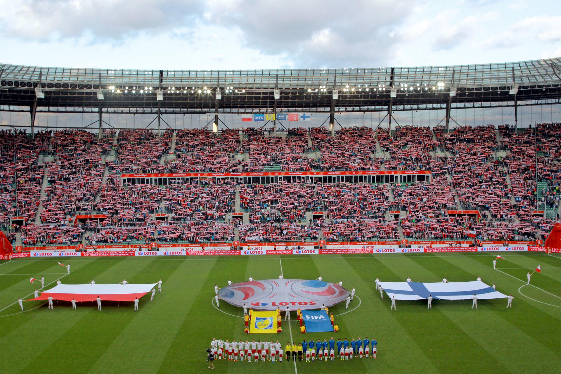 Reprezentacje Polski i Finlandii na boisku, w tle flagi obu państw. Towarzyskie spotkanie z 2016 roku.