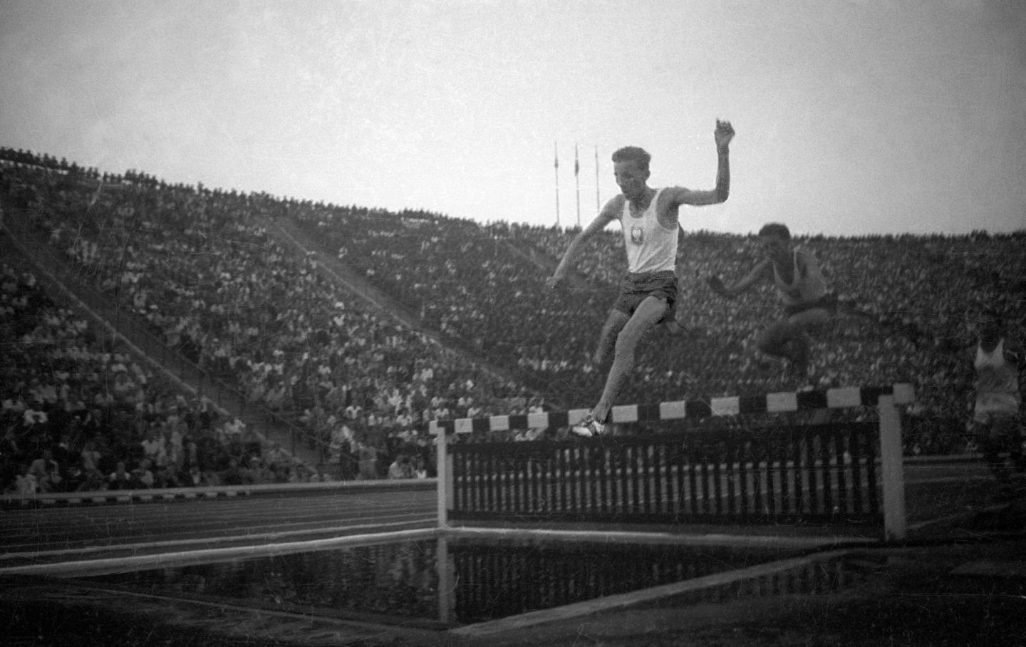Pierwsze dni sierpnia 1958 roku. Na trybunach Stadionu Dziesięciolecia około stu tysięcy widzów, a na bieżni, rzutniach i skoczniach największe gwiazdy sportu z Polski i USA podczas międzypaństwowego meczu lekkoatletycznego. Na zdjęciu dwóch bohaterów legendarnego wunderteamu: Jerzy Chromik (prowadzi, ustanowił w tym występie rekord świata) i Zdzisław Krzyszkowiak podczas biegu na 3000 metrów z przeszkodami.