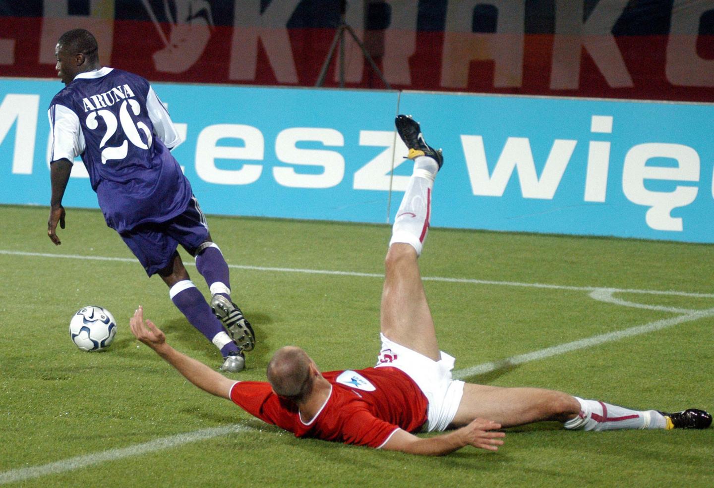 Aruna Dindané z Anderlechtu uciekający leżącemu na murawie zawodnikowi krakowskiej Wisły.