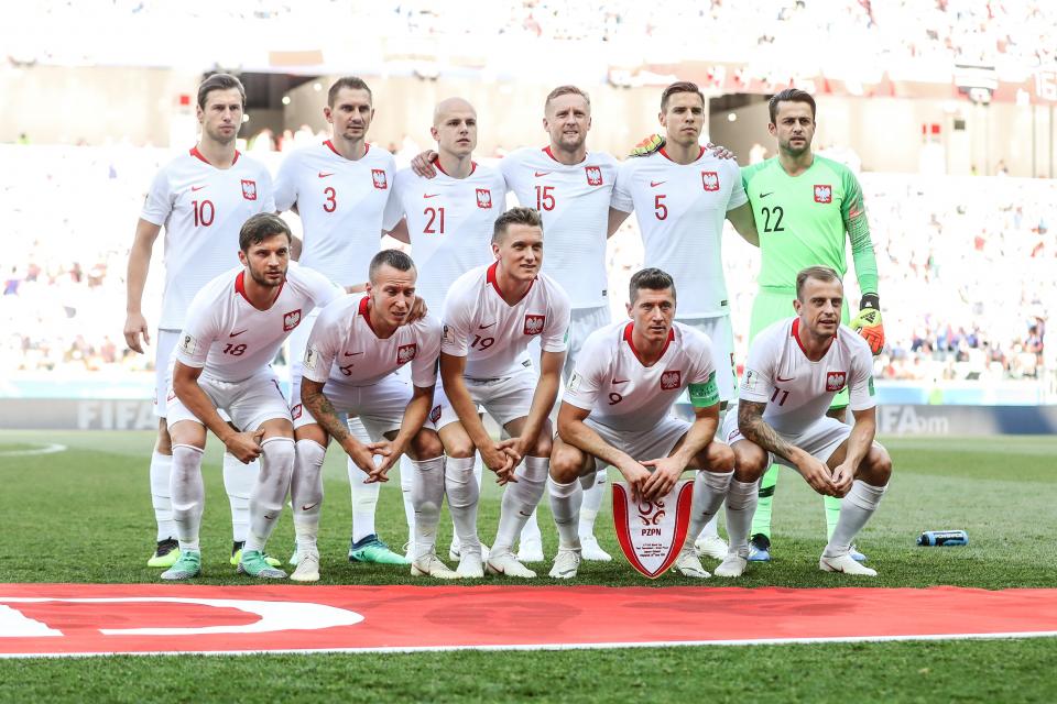 Reprezentacja Polski (w białych strojach) pozuje do zdjęcia przed meczem z Japonią. Bramkarz Łukasz Fabiański w jaskrawo-zielonym stroju.