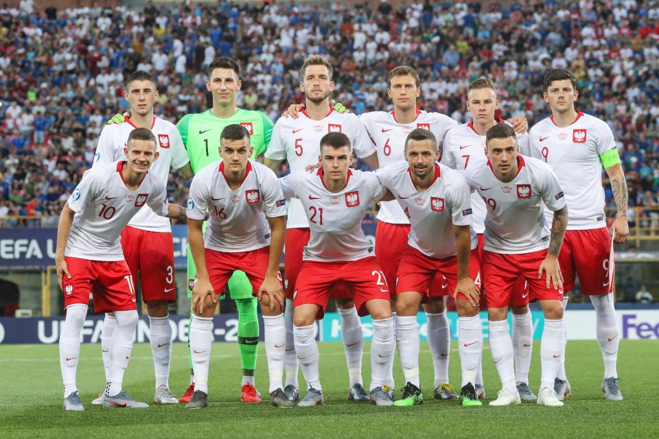 Reprezentacja Polski przed meczem z Włochami na młodzieżowych mistrzostwach Europy. Polacy w białych koszulkach z czerwonym kołnierzykiem oraz czerwonych spodenkach.